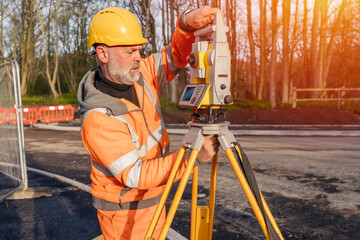 Site engineer setting his instrument during roadworks. Builder installing total positioning station...