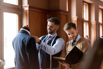 Tailors examining suit and taking notes in menswear shop