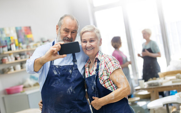 Senior couple taking selfie in pottery studio