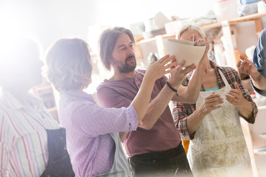 Mature students examining bowl in pottery studio