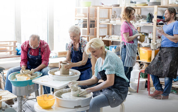 Mature students using pottery wheels in studio