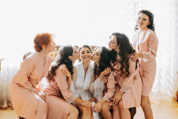 The bridesmaids look at the smiling bride. The bride and her cheerful friends are celebrating a...