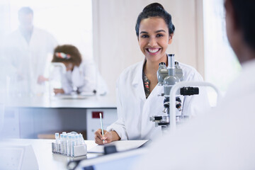 Smiling female college student conducting scientific experiment in science laboratory classroom
