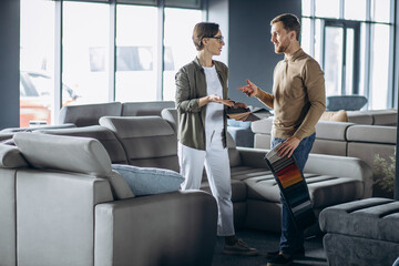 Woman and man designer with textile swatches and wooden palette at furniture store