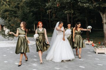 Beautiful bride and her friends- bridesmaids having fun after wedding ceremony. Happy girls at their best friend's wedding. Beautiful and elegant bride with bridesmaids walking on the stairs