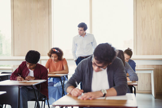 Professor watching college students taking test in classroom