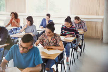 College students taking test at desks in classroom