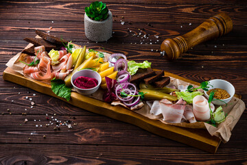 Russian banquet board with slices of bacon, boiled potatoes, red onion rings, pickles, garlic...
