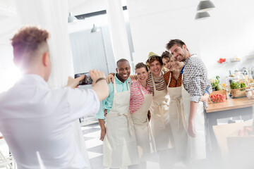 Naklejka premium Chef teacher photographing students camera phone in cooking class kitchen