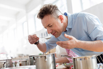 Man smelling food leaning over pot in cooking class kitchen