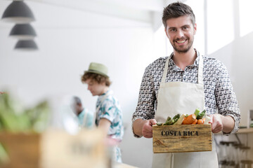 Portrait smiling man holding fresh vegetables in cooking class kitchen