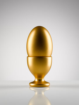 Golden egg in egg cup holder against white background