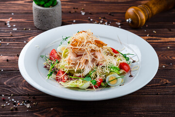 Italian food Caesar salad with chicken, parmesan cheese, quail eggs, lettuce, tomatoes and croutons.