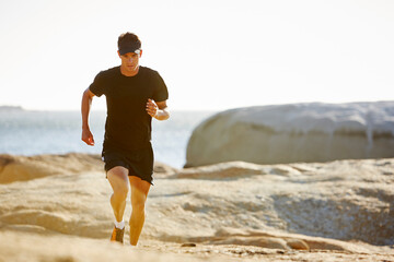 Male triathlete running on sunny rocky trail