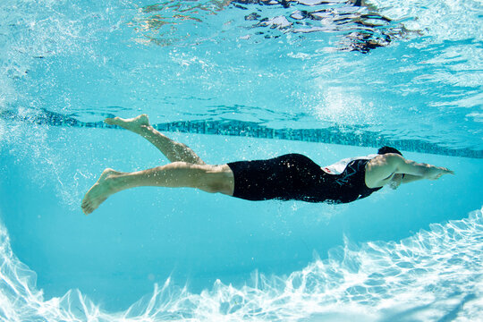 Male swimmer athlete swimming underwater in swimming pool