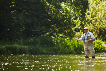 Fototapeta na wymiar Senior man fly fishing at summer river