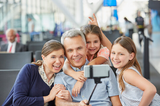 Family taking selfie with selfie stick at airport
