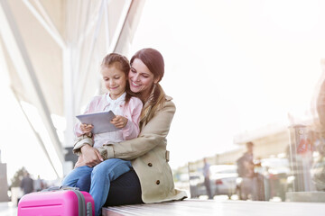 Mother and daughter using digital tablet outside airport - obrazy, fototapety, plakaty