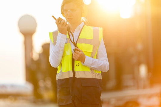 Air traffic controller using walkie-talkie on airport tarmac