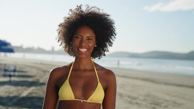 Close up portrait of attractive black woman smiling on bikini at the beach on a sunny day
