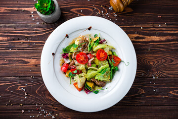 Green salad with cherry tomatoes, pork, lettuce and green peas.