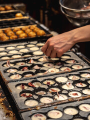 Process to Cooking Takoyaki on hot pan Famous food Osaka Japan street food. Making takoyaki filled with octopus pieces on a hot pan in the street food festival. Popular street food in Osaka.
