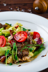 Salad with cherry tomatoes, pork, lettuce and green peas, fresh meal.