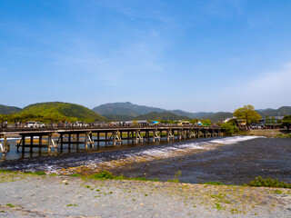 Arashiyama Bridge, an enchanting wooden structure, gracefully arches over the tranquil waters of the Hozu River. Adorned with vibrant foliage, it invites visitors to step into a world of serenity.