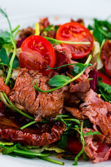 Green salad with cherry tomatoes, beef, cucumbers, sun-dried tomatoes, lettuce, arugula and green peas, fresh dish.