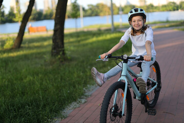 Cheerful child girl rides a bicycle along the bike path.