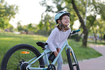 Little girl child fools around and takes out a bottle of water from a bicycle.