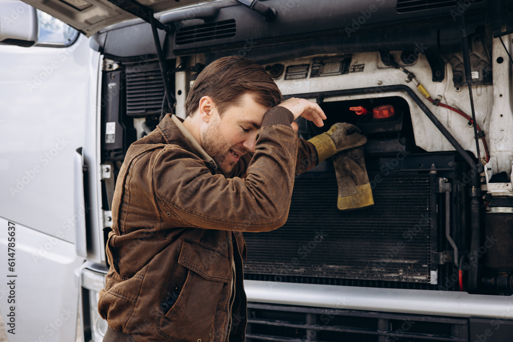 Wall mural truck driver stopped on the road reparing his lorry