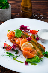 Fried potato pancakes with salmon, capers, tomatoes, lettuce and sour cream.