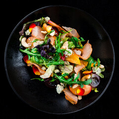 Salad with bacon, persimmon, arugula, olives, blue cheese, cashews and lettuce, lunch.