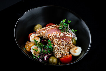 Fish salad with raw tuna, cherry tomatoes, olives, quail eggs and microgreens.