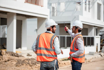 Structural engineer and foreman wearing hardhat for working together at construction site,...