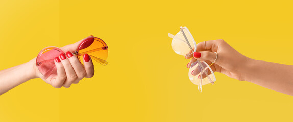 Female hands with beautiful manicure holding glasses on color background