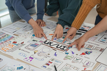 UX developer and UI designer brainstorming about app interface wireframe design on table with customer brief at modern office. Creative digital development agency