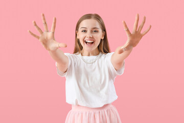 Happy young woman in t-shirt showing hands on pink background