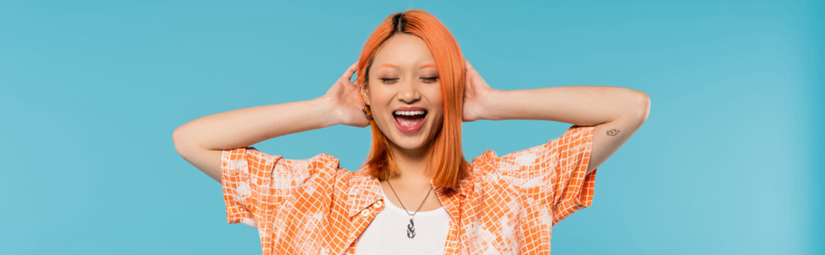 positivity and happiness, young asian woman with dyed hair standing with closed eyes in orange shirt and smiling on blue background, casual attire,  freedom, cheerful attitude, tattoo, banner