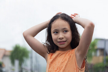 Girl under the summer rain close-up.Portrait of an asian girl enjoying the light rain with cute smile. 