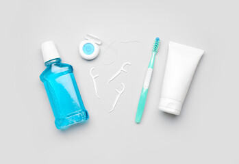 Rinse, dental floss, brush and tube of toothpaste on grey background