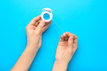 Woman holding dental floss on blue background