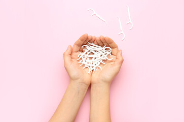 Woman holding many floss toothpicks on pink background