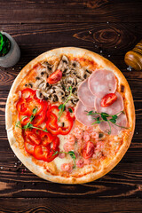 Fototapeta na wymiar Pizza with ham, shrimp, mushrooms, cheese, sweet peppers, tomatoes and microgreens, Italian cuisine.