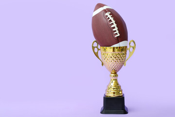 Gold cup with rugby ball on lilac background