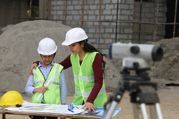 Young Indian School kids working as a role model engineer on a builder construction site working on...