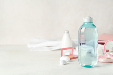 Bottle of micellar water with cotton pads on white table, closeup