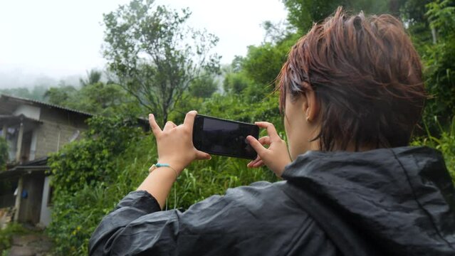 Female tourist taking pictures of local village at Sinharaja Forest Reserve.