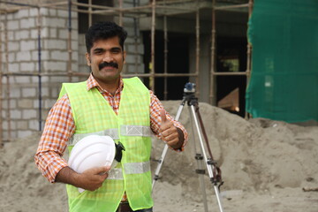 Hardworking Indian Site engineer figuring out the work in progress. On the site location wearing the uniform and helmet in white. Stylish and flamboyant engineer on the construction site, working hard